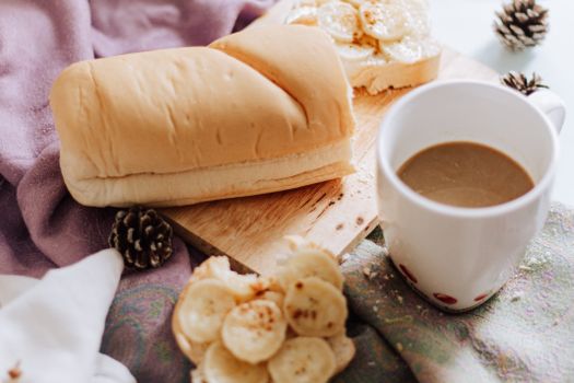 A warm and inviting breakfast scene with bread, coffee, and banana-topped toast.