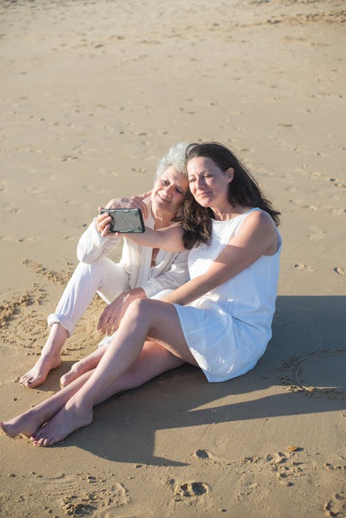 Free Women Taking Selfie While Sitting on Shore Stock Photo