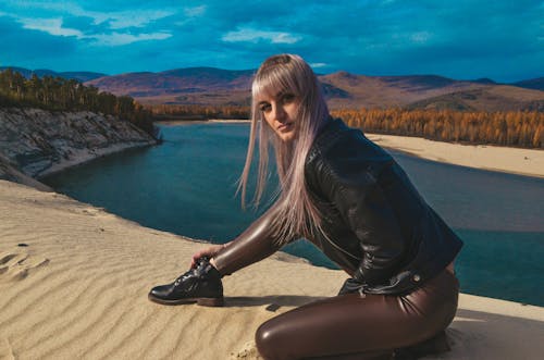Free Woman in Leather Jacket Sitting on Sand Stock Photo