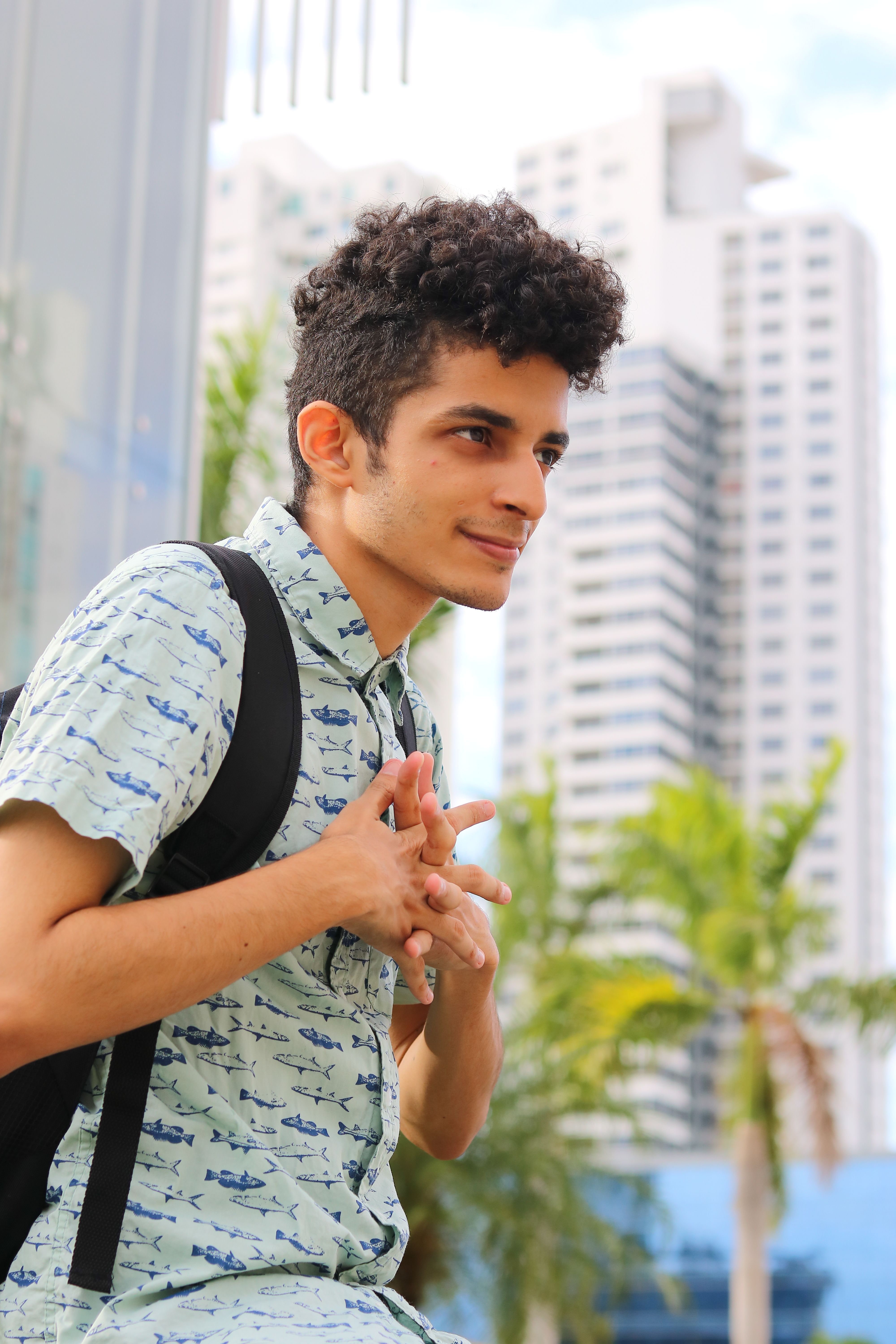 Portrait of a young man with curly hair in Panama City's urban environment. Bright daytime scene.