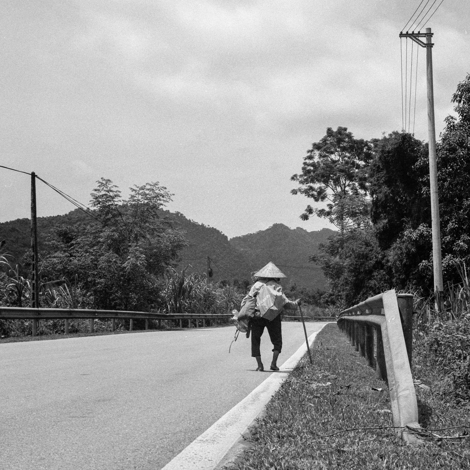 Person walking along a rural road in Ha Giang showing the quiet rhythm of the journey