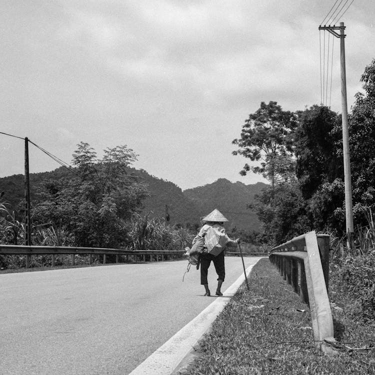 A Person Walking With A Stick On A Road