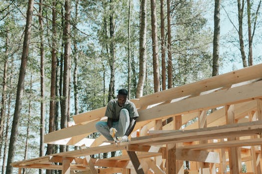 An adult man working on a wooden construction project in a sunny forest setting.