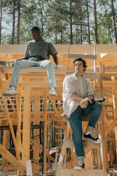 Two young men sit at a construction site, showcasing teamwork and industry outdoors.