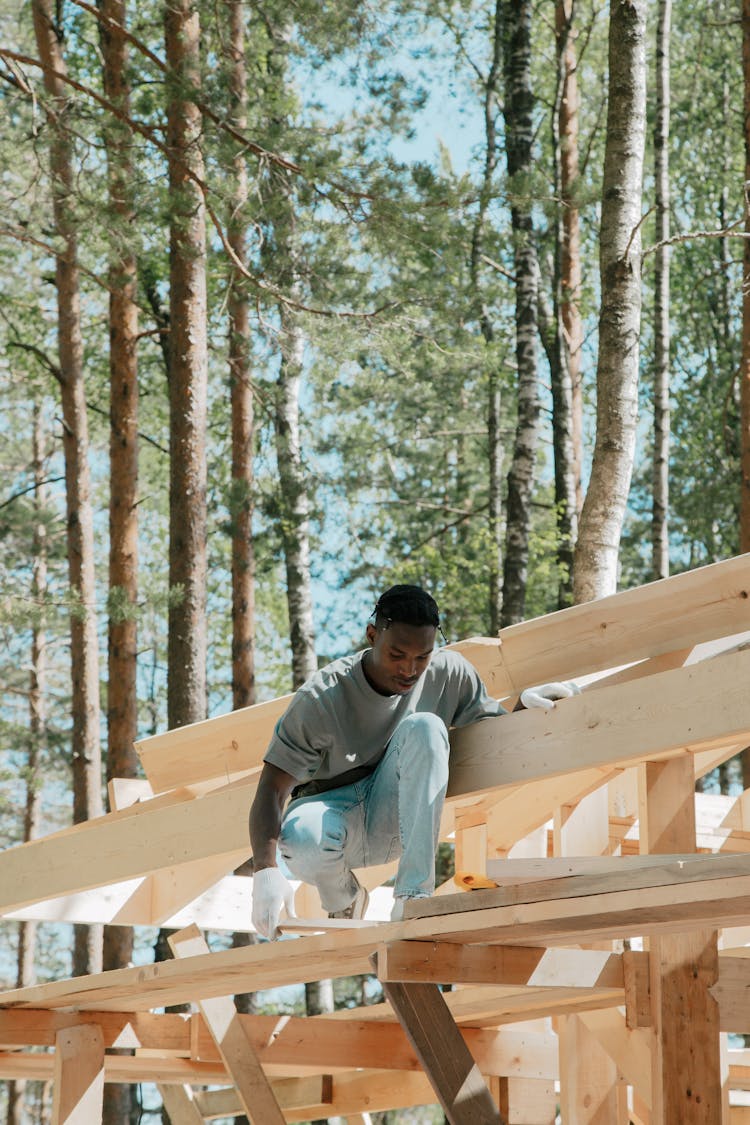 Man Squatting On Wooden Structure