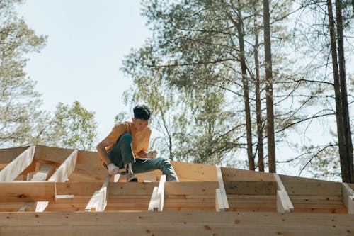 Construction Worker seated on Wooden Trusses