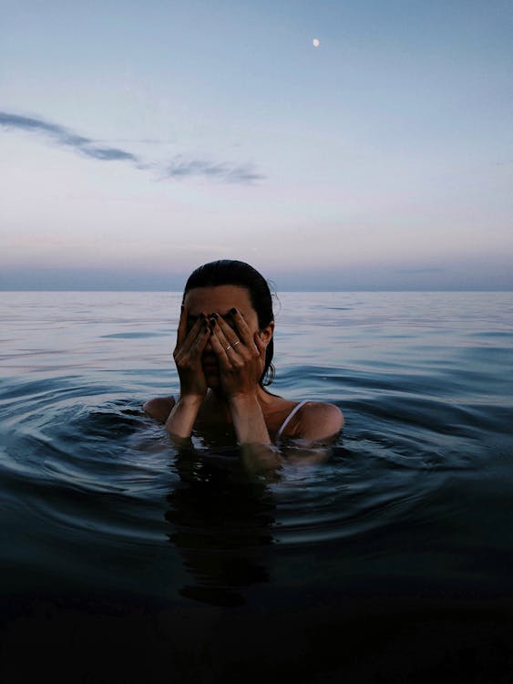 Woman in Body of Water covering her Face