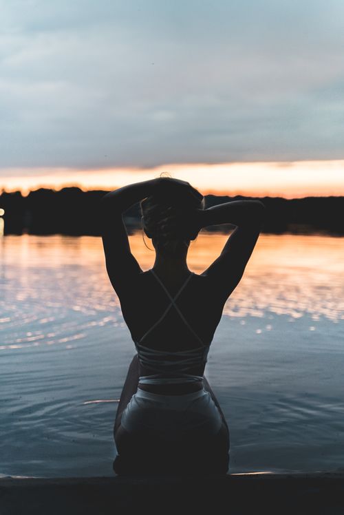Free A serene moment as a woman enjoys the sunset by a lake, captured in Ślesin, Poland. Stock Photo