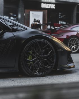 Luxury sports cars parked on an urban street in Poznań, showcasing sleek design and modern architecture in the background.