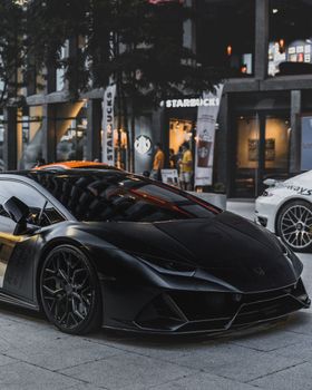 Matte black luxury sports car parked in Poznań city center, showcasing sleek design.