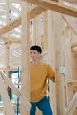 Man in Yellow Crew Neck Long Sleeve Shirt Standing Beside Brown Wooden Fence
