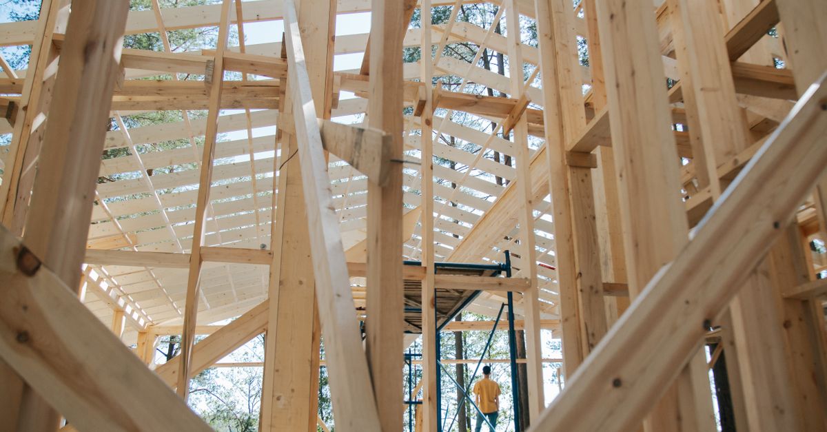 Innenansicht eines Holzrahmenhauses im Rohbau mit sichtbaren Holzständern und Sparren.