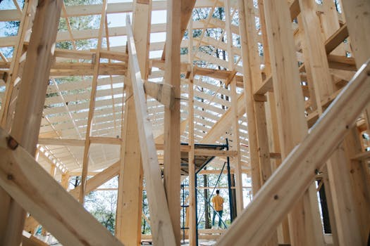 Interior view of wooden house frame under construction with visible scaffolding.