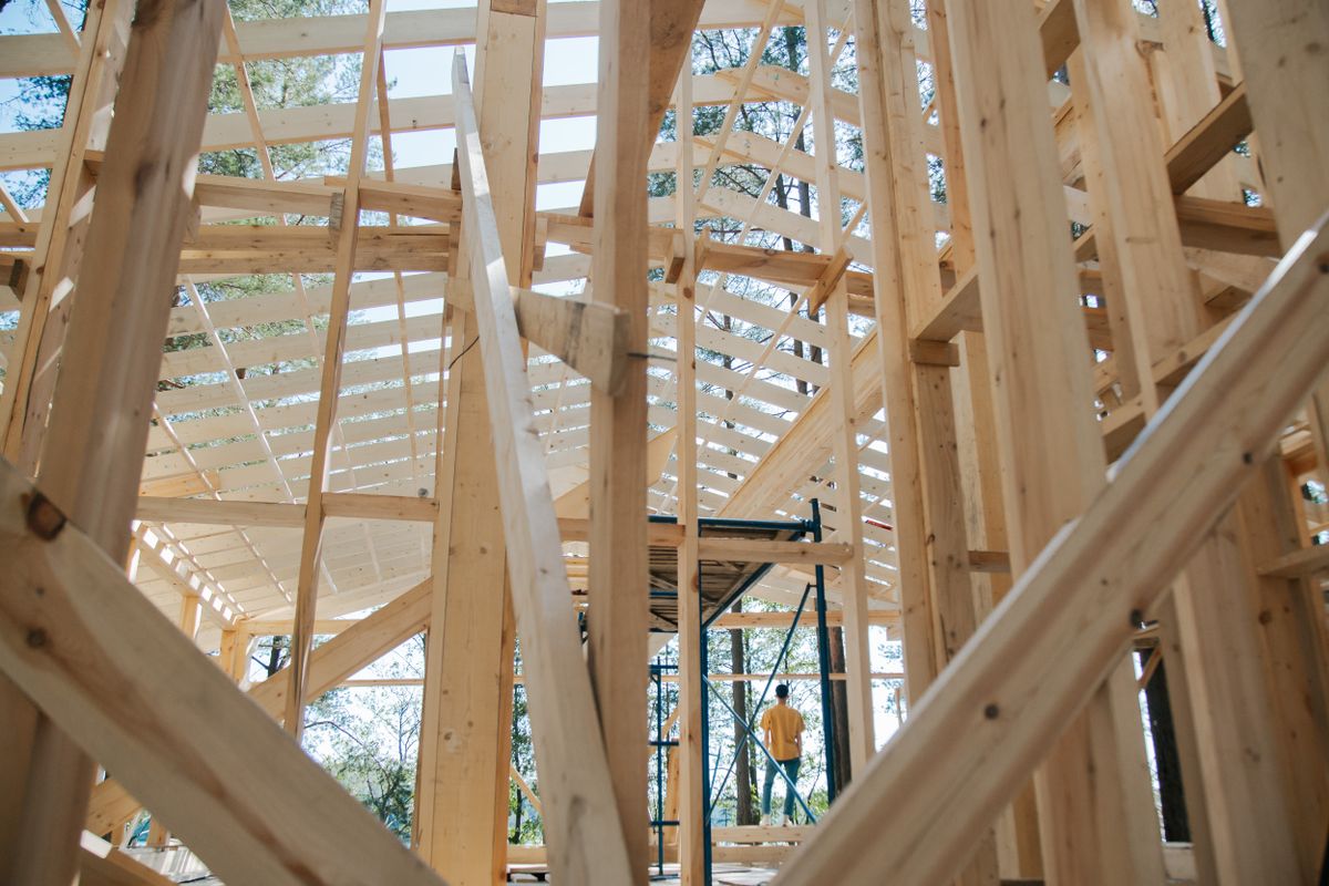 Wood-framed house under construction with exposed studs and scaffolding