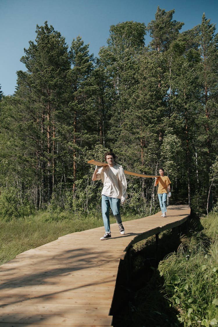 Two Men Carrying A Wooden Plank