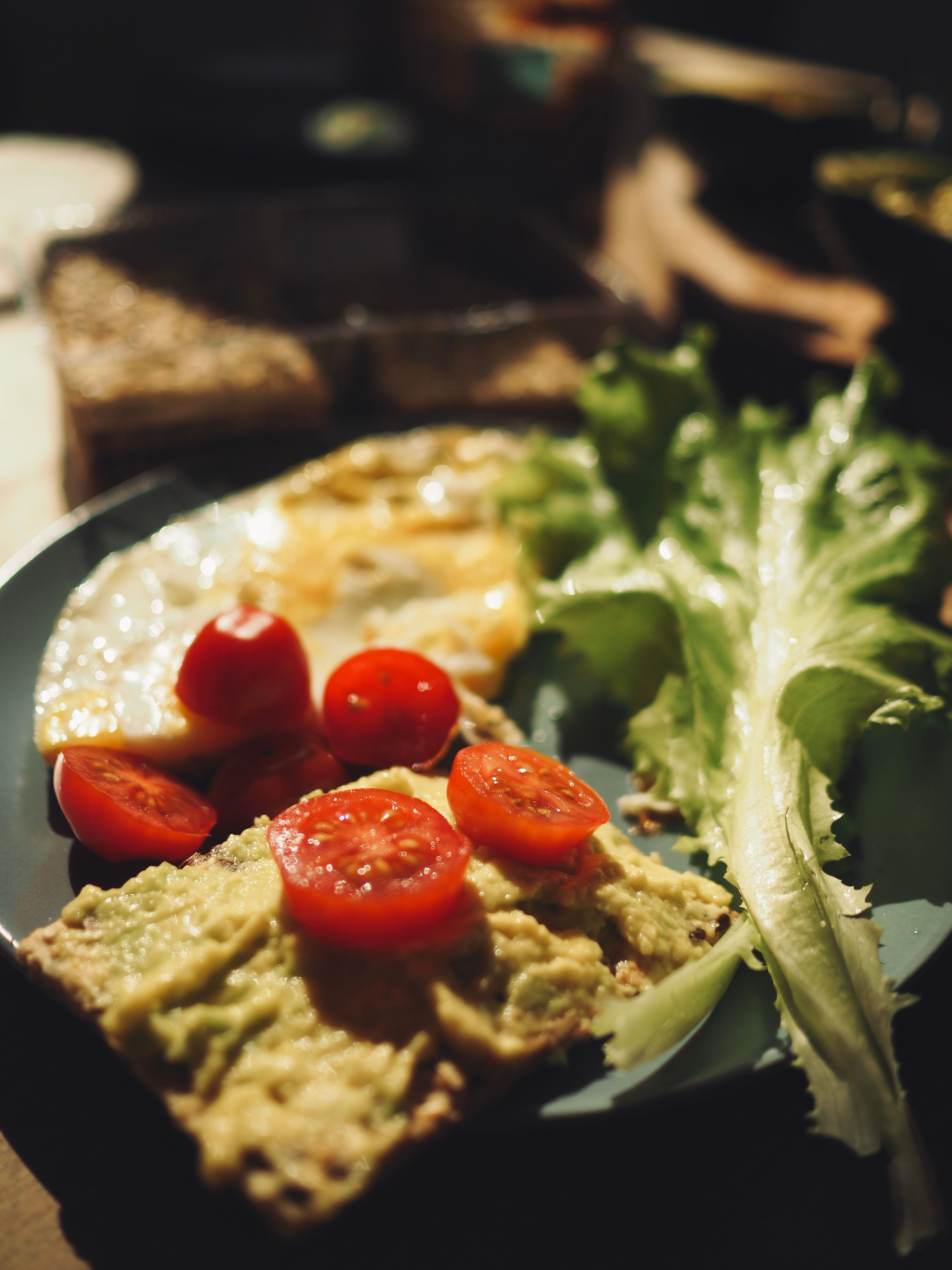Savor a nutritious breakfast featuring avocado toast with cherry tomatoes, fresh greens, and a fried egg.