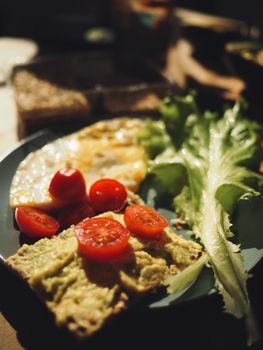 Savor a nutritious breakfast featuring avocado toast with cherry tomatoes, fresh greens, and a fried egg.