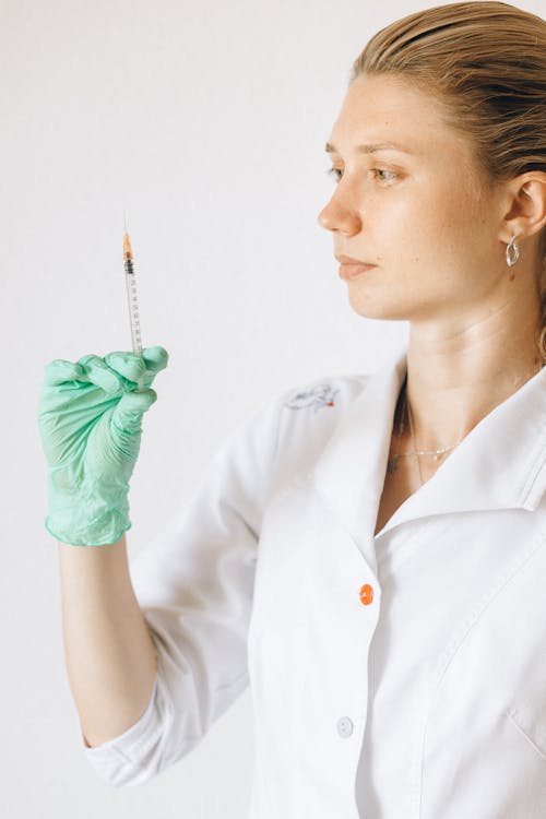 Woman in White Uniform Holding an Injection