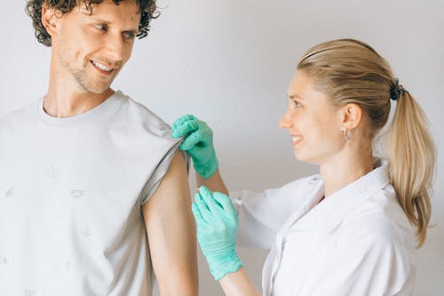 Woman in White Uniform Giving Man a Vaccine