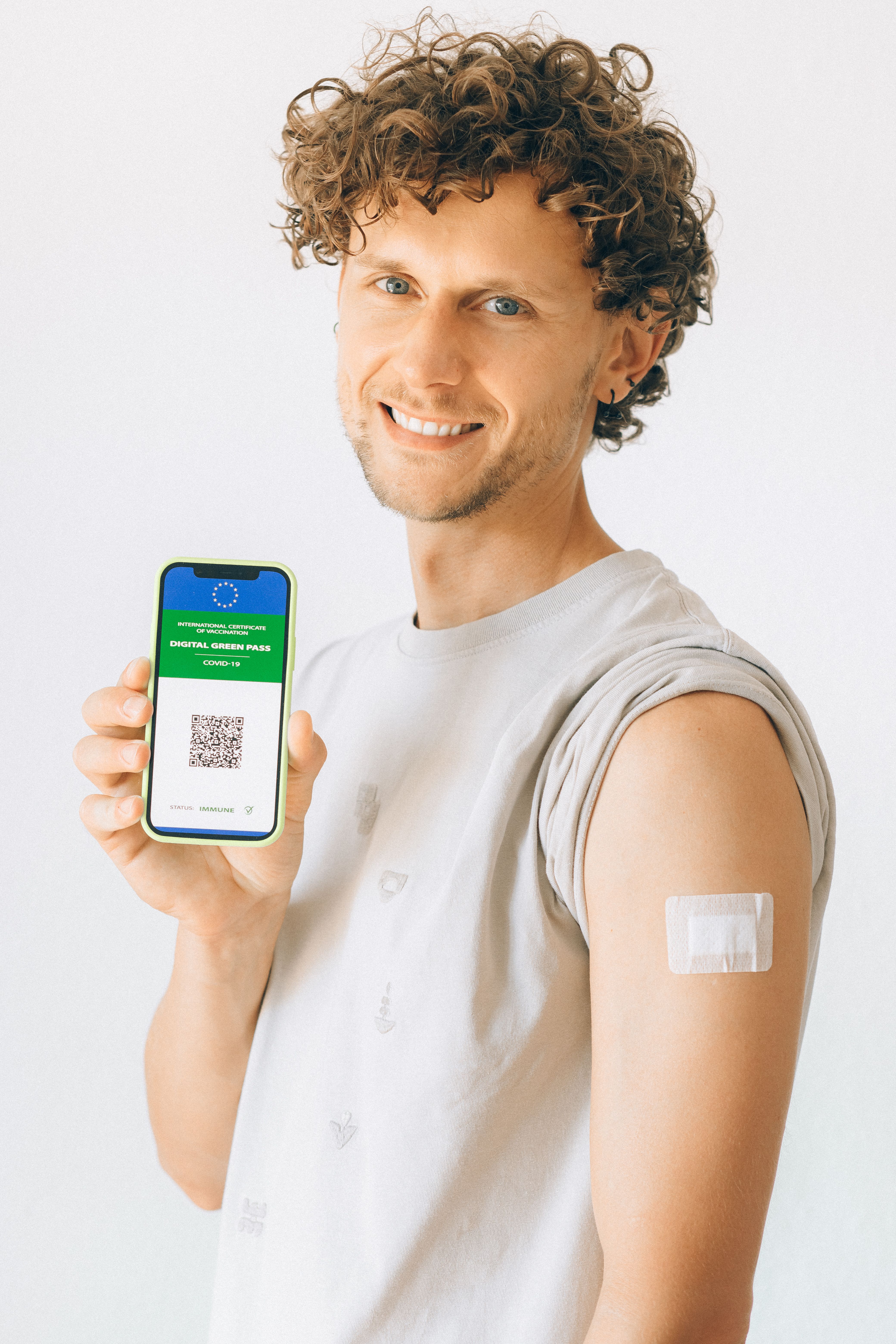 Caucasian man smiles while displaying a digital COVID-19 vaccination passport on his smartphone.