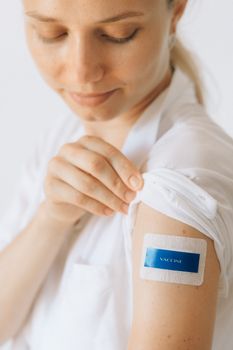 Close-up of a woman displaying a vaccination bandage on her arm, promoting healthcare and protection.