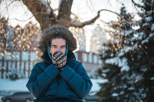 Man in a Winter Coat Blowing on Hands in Mittens 