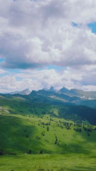 Lush green landscape with distant mountains under a vibrant sky in Yermakovsky District, Russia.
