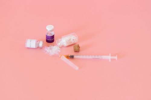 Free Conceptual image of vaccine vials and syringe on a soft pink background. Stock Photo