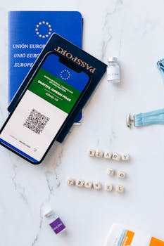 Digital Green Pass with passport and travel essentials on marble surface.