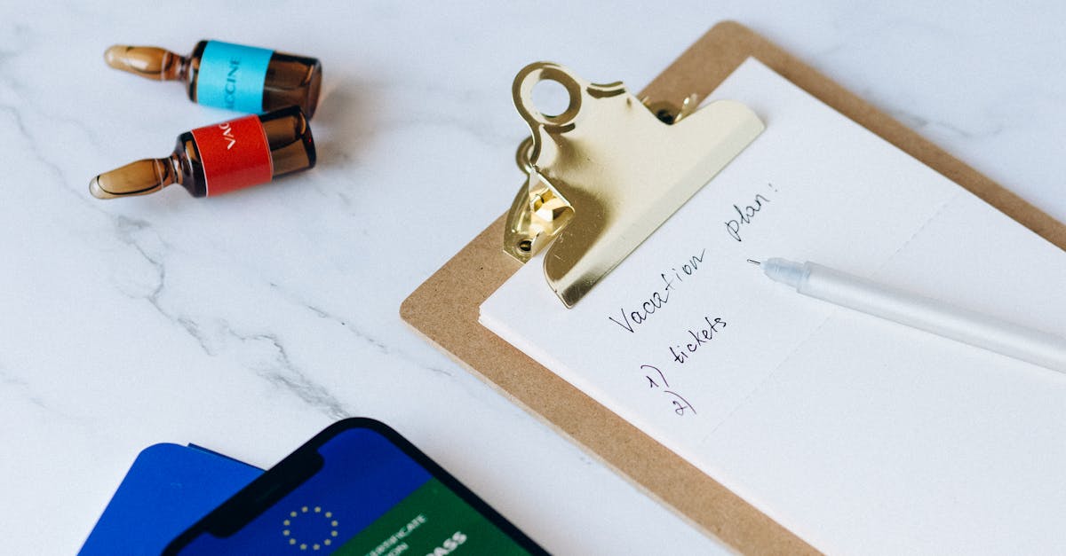 A flat lay of a smartphone showing a vaccine passport, passport, clipboard, and vaccines, symbolizing travel readiness and COVID-19 safety measures.
