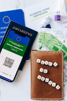 Flat lay of travel items including passport and digital COVID-19 certificate.