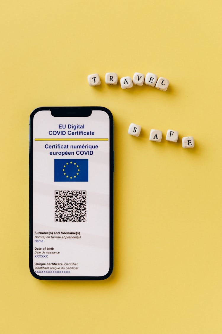 A Cellphone With Screenshot Of Covid Certificate On A Yellow Surface