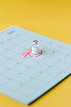 A vaccine vial placed on a calendar, highlighting a scheduled vaccination appointment.