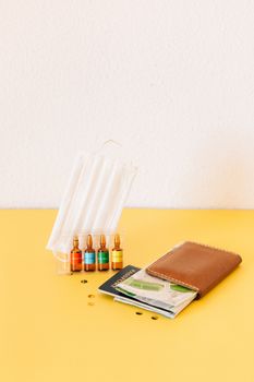 A creative still life of travel essentials during the pandemic including a mask, passport, and vaccine vials.