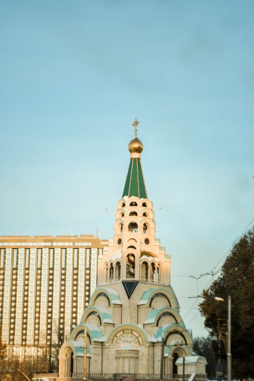 Free Elegant Orthodox church with a golden dome against a city skyline at twilight. Stock Photo
