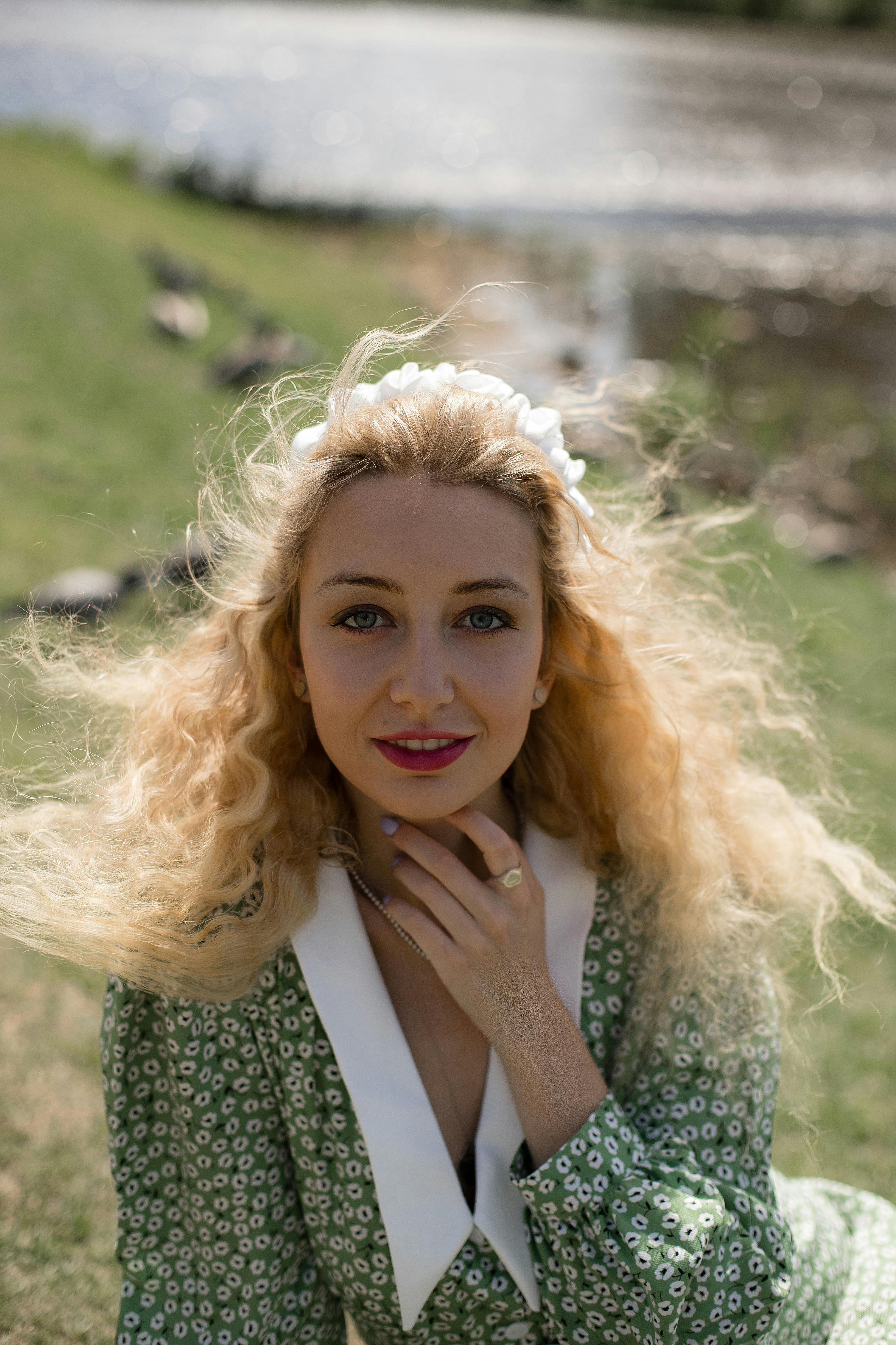 Portrait of a blonde woman with curly hair in a green floral dress, outdoors in Moscow.