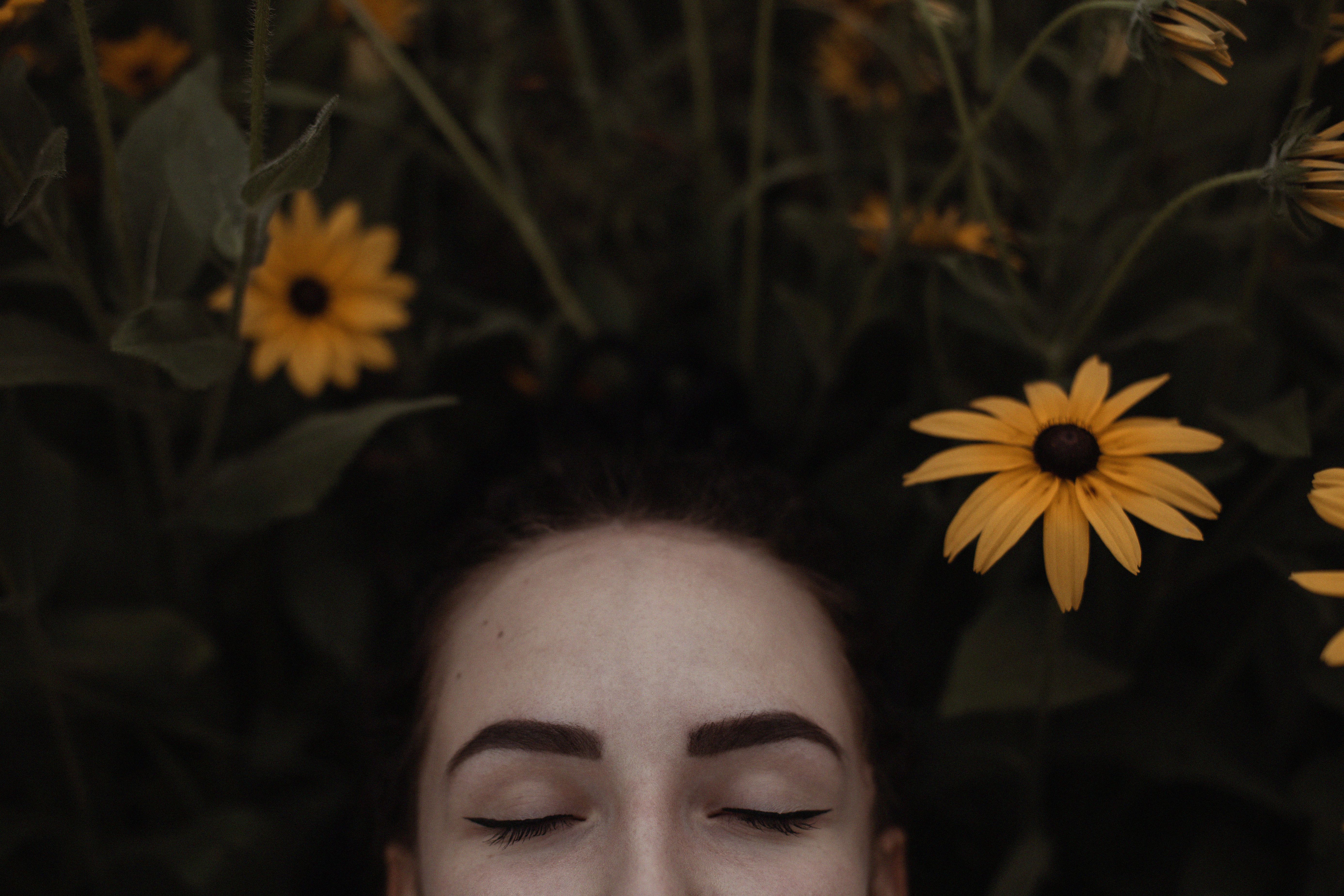 A peaceful portrait of a woman surrounded by vibrant yellow Black-Eyed Susans in a lush garden.
