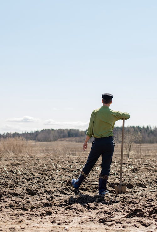 Man Standing on the Field with a Shovel 