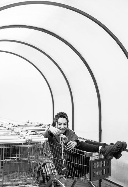 Happy woman enjoying a fun moment sitting inside a shopping cart.