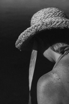 Elegant black and white portrait of a woman wearing a straw hat on a summer day.