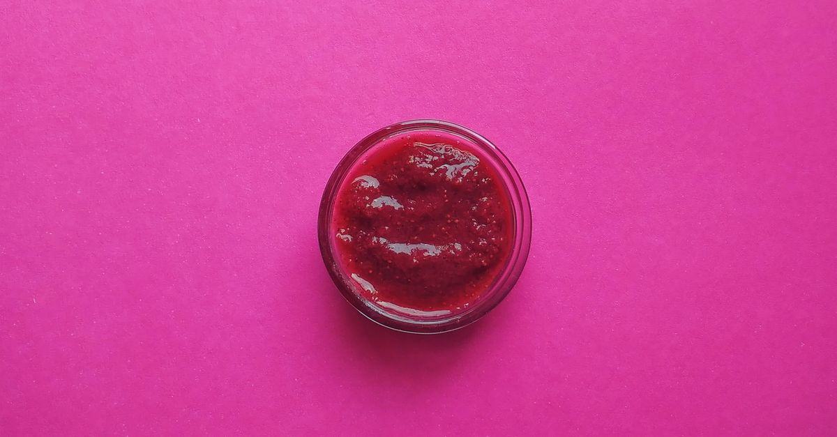 A Round Container with Red Jam on a Pink Surface · Free Stock Photo
