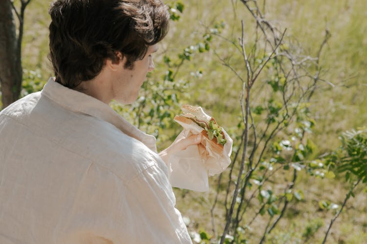 A Man Looking At The Sandwich He Is Holding