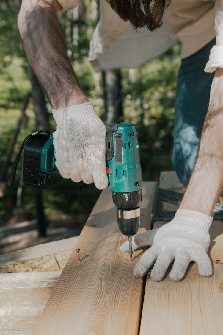 A Person Drilling The Screwdriver On The Wooden Surface