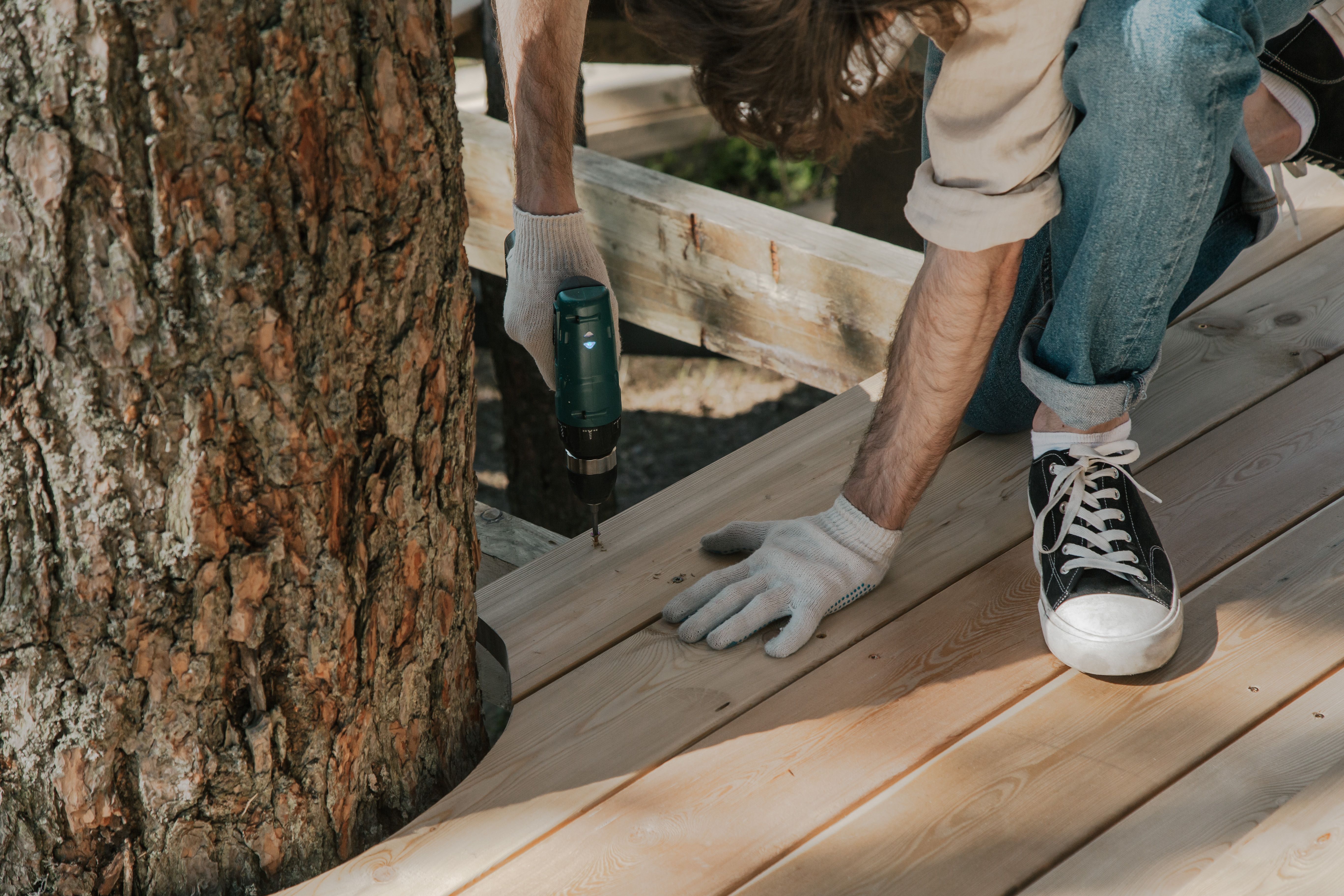 Artisan vissant des lames de terrasse en bois pendant une rénovation