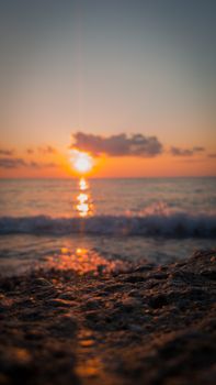 A serene sunset over the ocean with waves crashing on the sandy shore, capturing the beauty of golden hour.