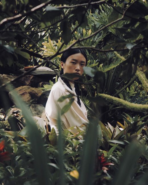 A contemplative woman surrounded by vibrant greenery in an Orlando garden.