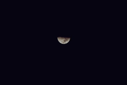 A peaceful view of a half moon glowing softly against a dark night sky, symbolizing tranquility.