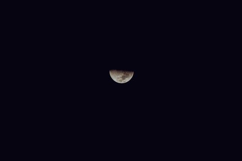 Free A peaceful view of a half moon glowing softly against a dark night sky, symbolizing tranquility. Stock Photo