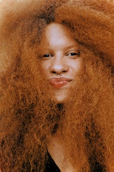 Close-up portrait of a woman with vibrant red curly hair and nose ring in Miami.
