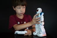 Boy in Red T-shirt Holding White and Blue Robot Toy